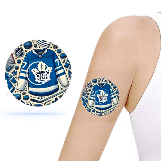 En arm som bär en CGM-patch med Toronto Maple Leafs design, inklusive lagets emblem och färger, perfekt för ishockeyfans.